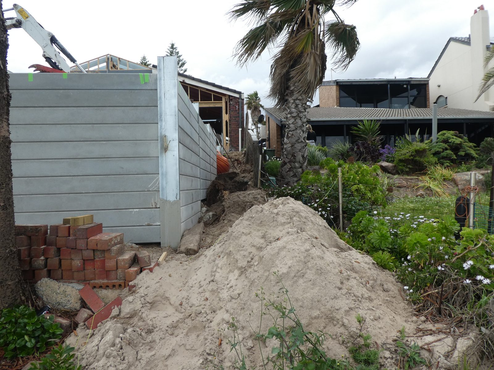 Concrete sleeper retaining wall during construction beside a house